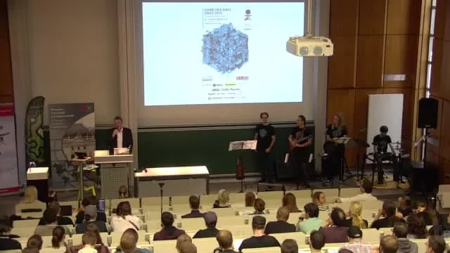 Band on stage in front of a full lecture hall at Game Dev Days 2019, from the TUbe recording